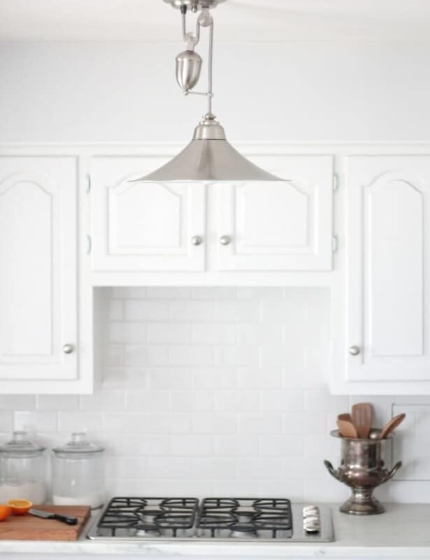 A silver light fixture in a white low budget kitchen renovation.
