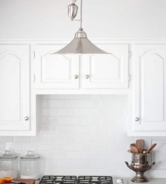 A silver light fixture in a white low budget kitchen renovation.