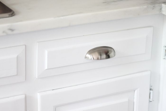 A white kitchen cabinet with a silver pull for farmhouse kitchen ideas on a budget.