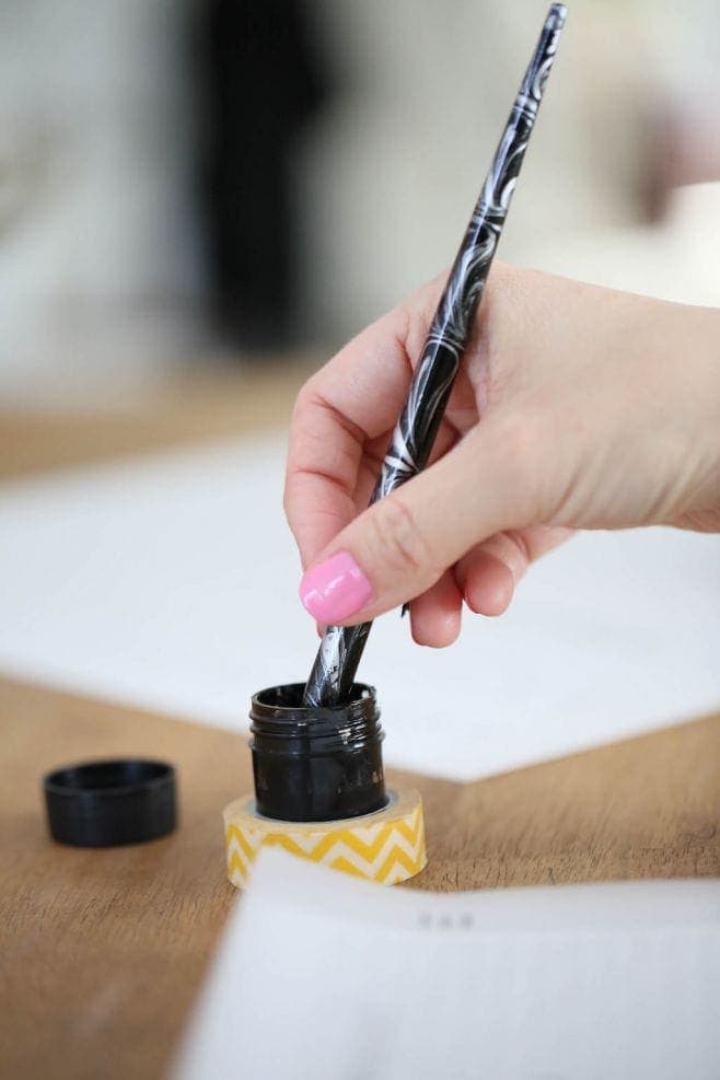 A calligraphy pen being dipped into ink. 