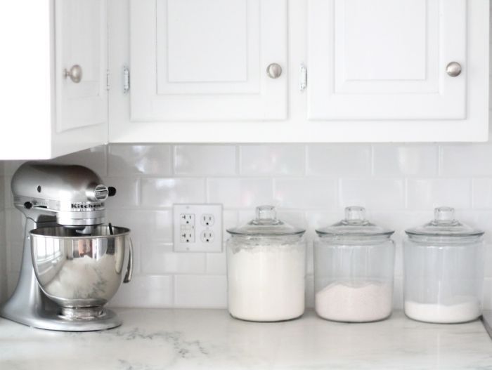 a classic white kitchen with marble countertops & white subway tile