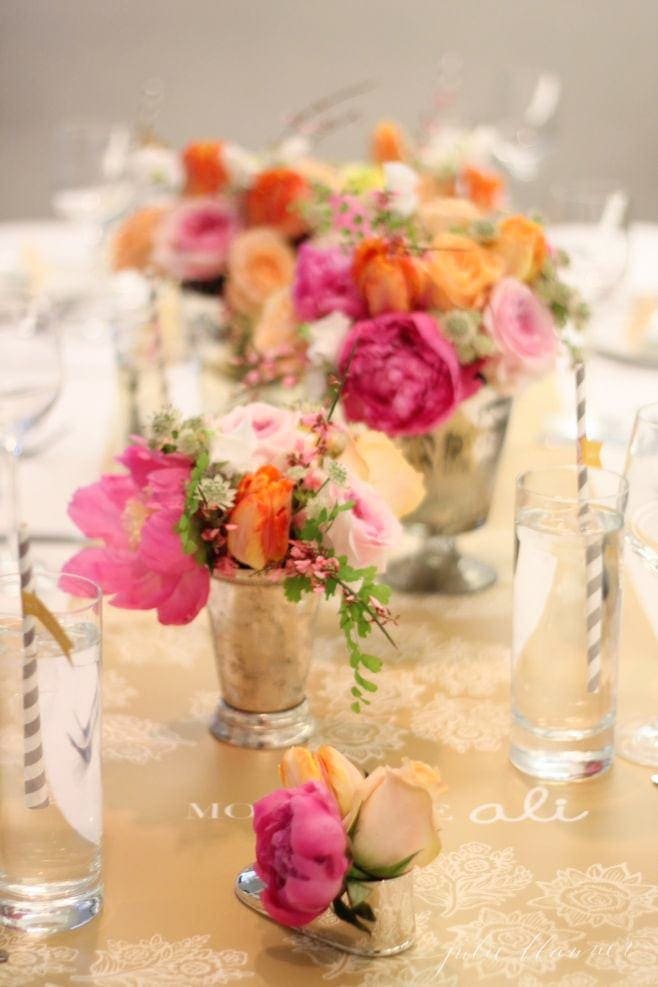 A set table with pink and orange flowers on it.
