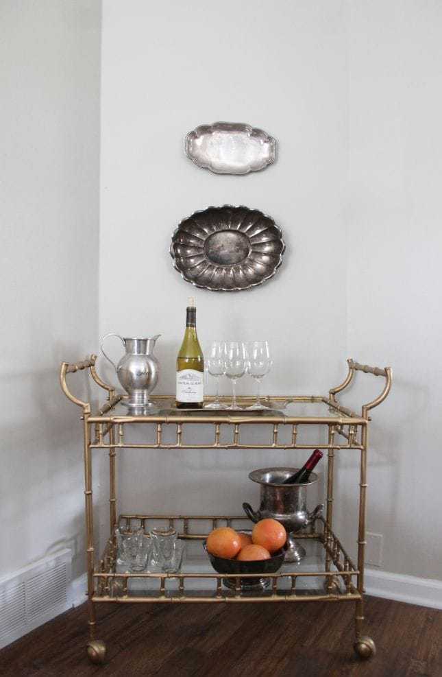 A dining room painted in Sherwin Williams Accessible Beige, with a gold bar cart in the corner. 