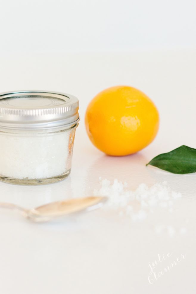 A clear glass mason jar of sugar scrub with a single orange in the background.