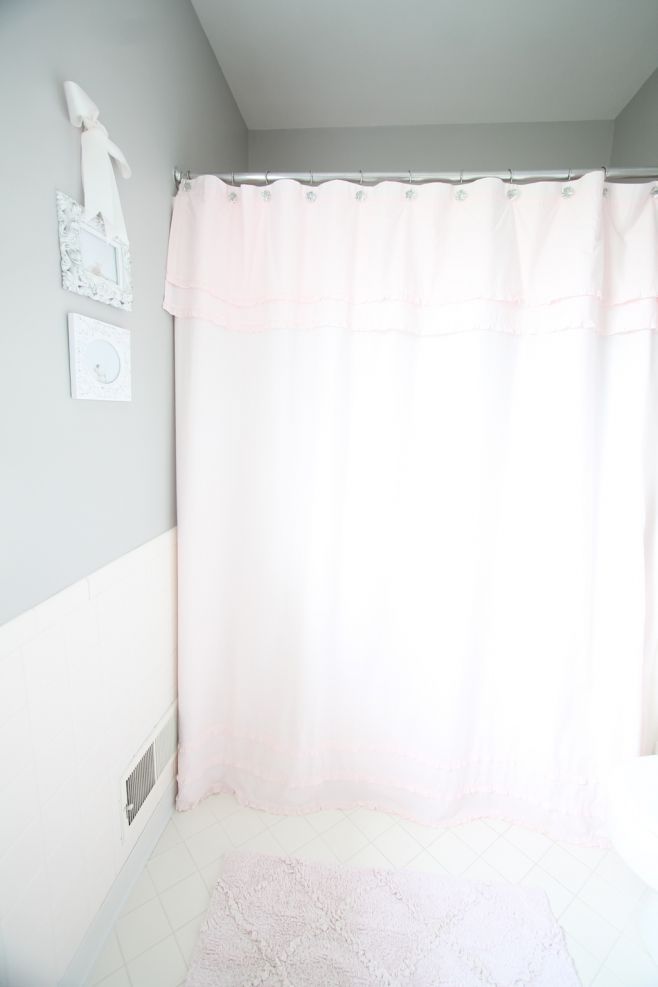 A bathroom with gray walls and a soft pink shower curtain.