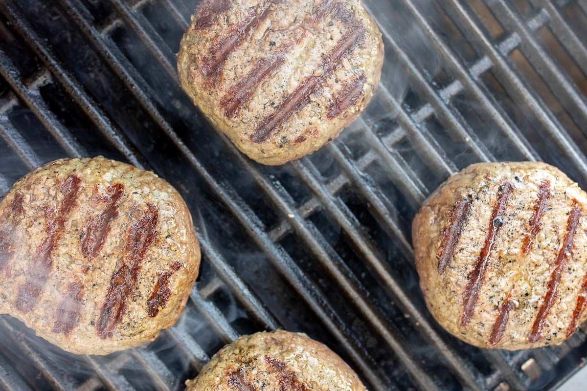 Grilled burgers with perfect grill lines on a smoking gas grill grate.