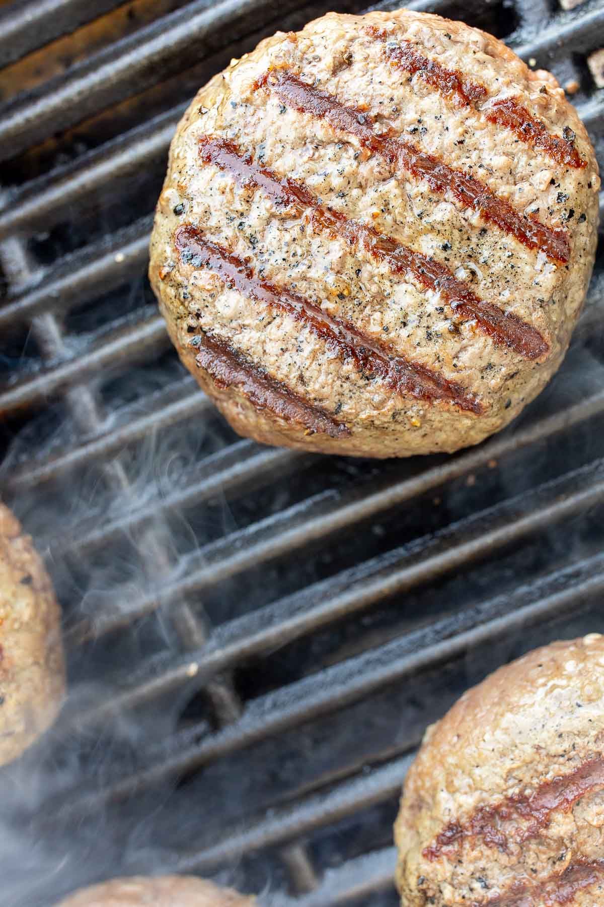 A grill with burgers cooking on the grill grate