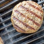 A perfectly charred grilled burger on a smoking gas grill grate