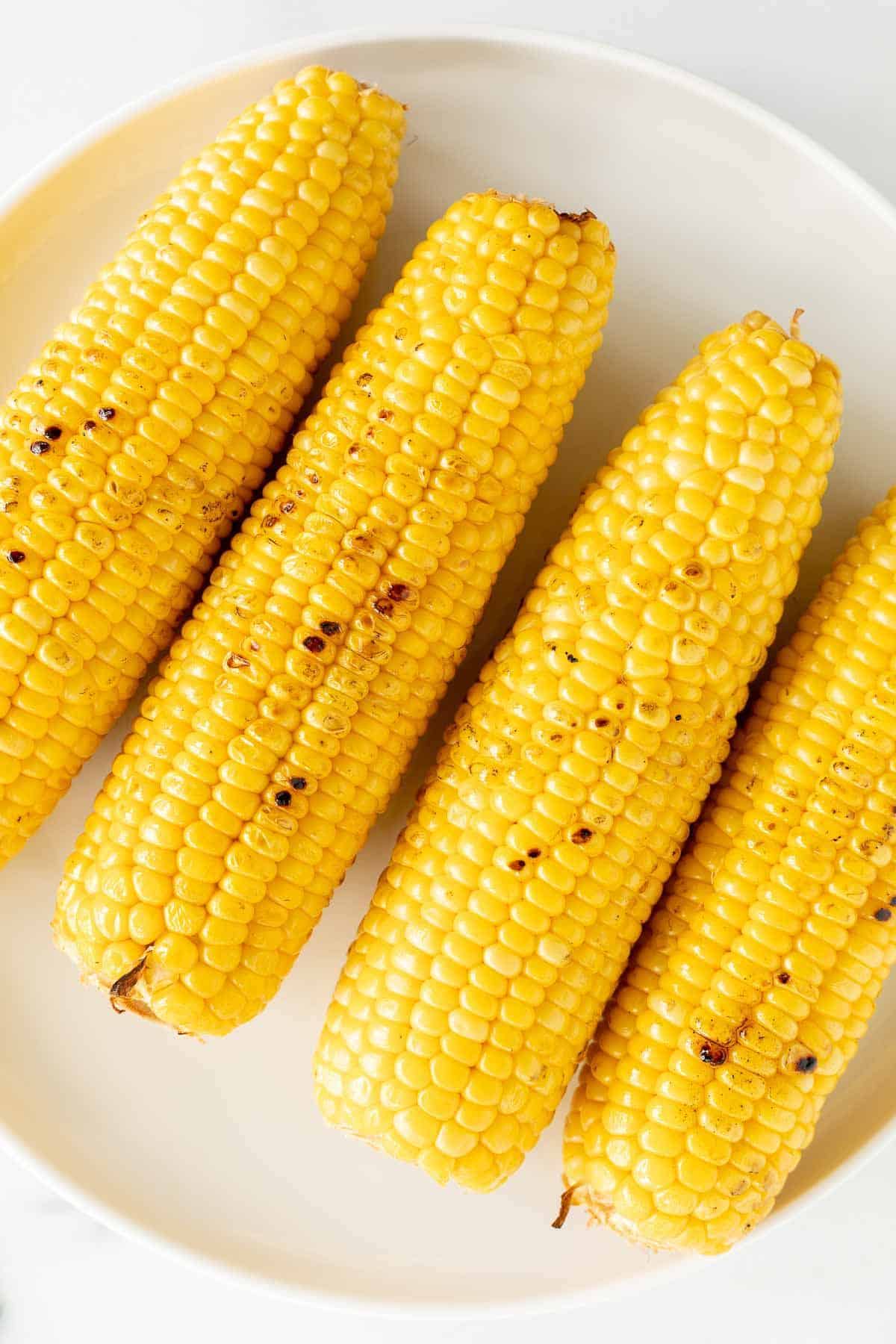 grilled corn on the cob on a white plate