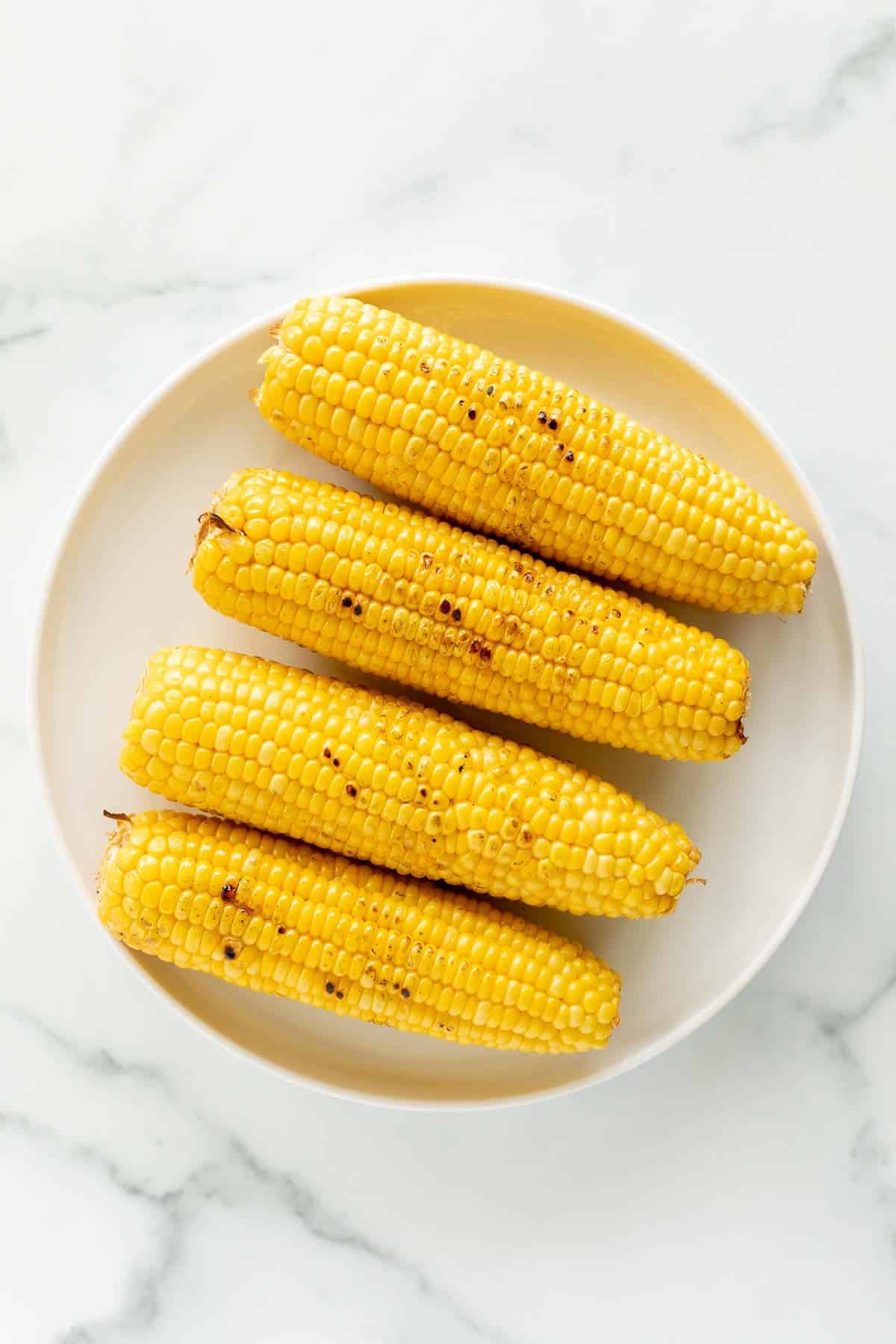 Grilled corn on the cob on a white plate for a side dish for fish