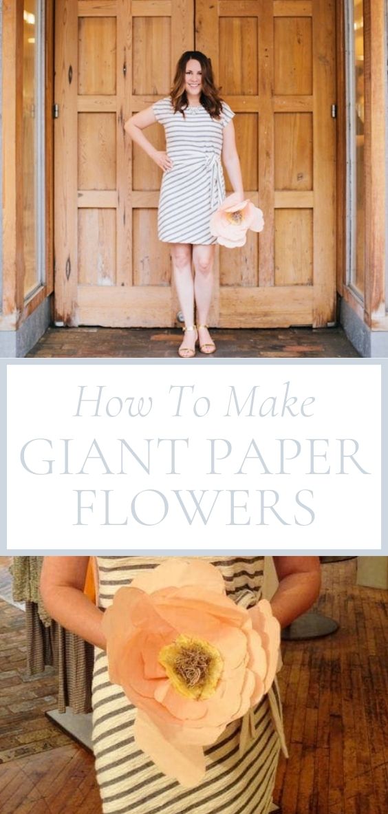 Julie Blanner is standing on a brick ground in front of double wooden doors holding a giant paper flower.