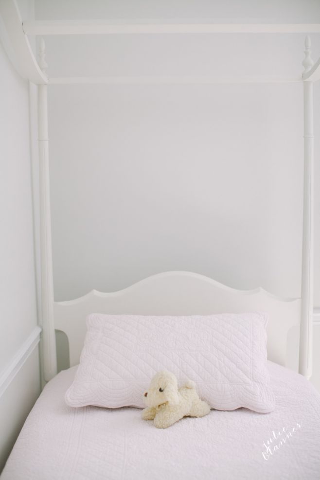 A four poster bed in a white and blush pink girls bedroom