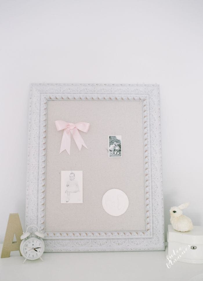 A linen pin board on a white dresser in a pink girls bedroom.