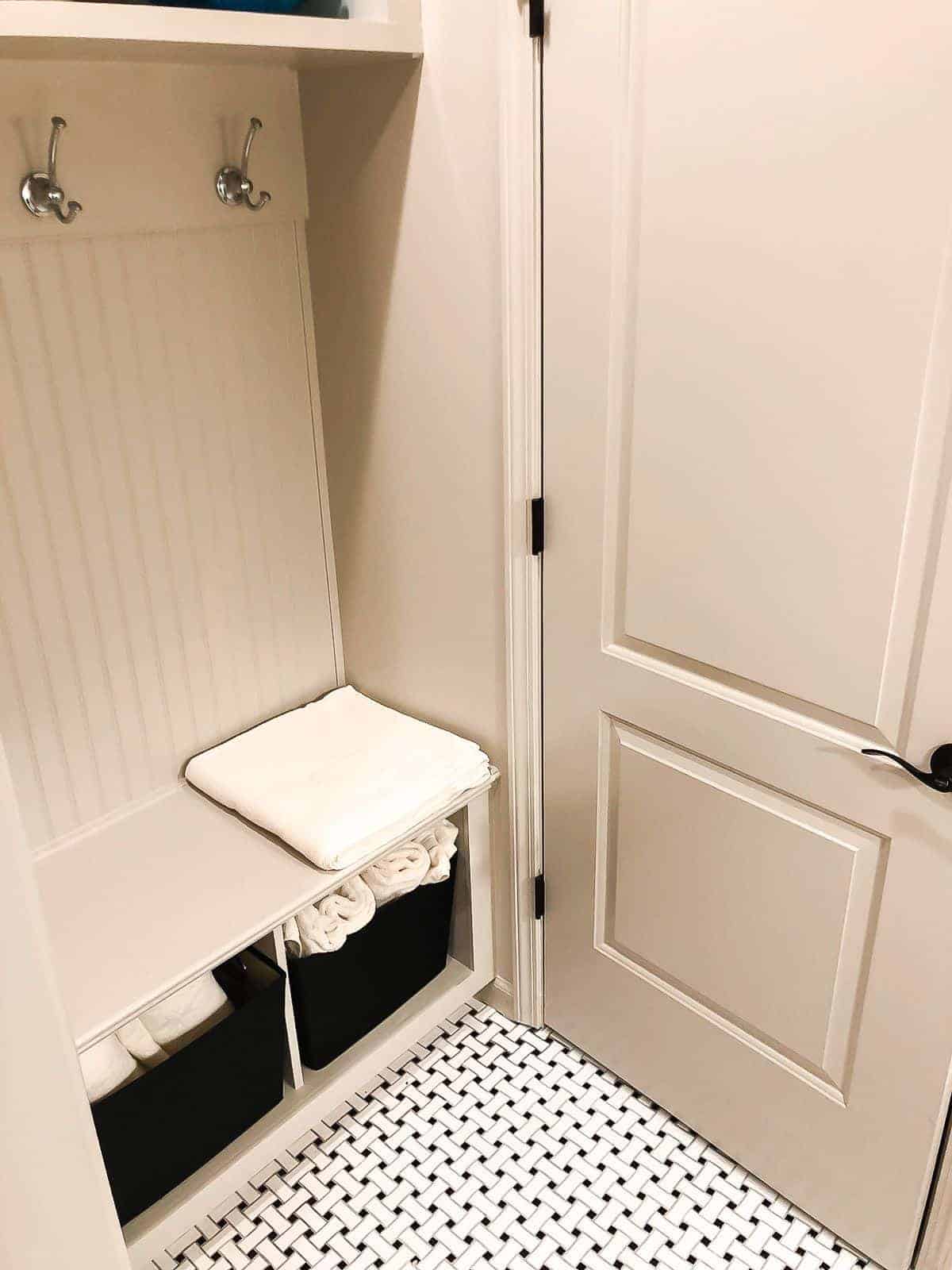 SW Accessible Beige in a small bathroom with a built in cabinet and a black and white floor.