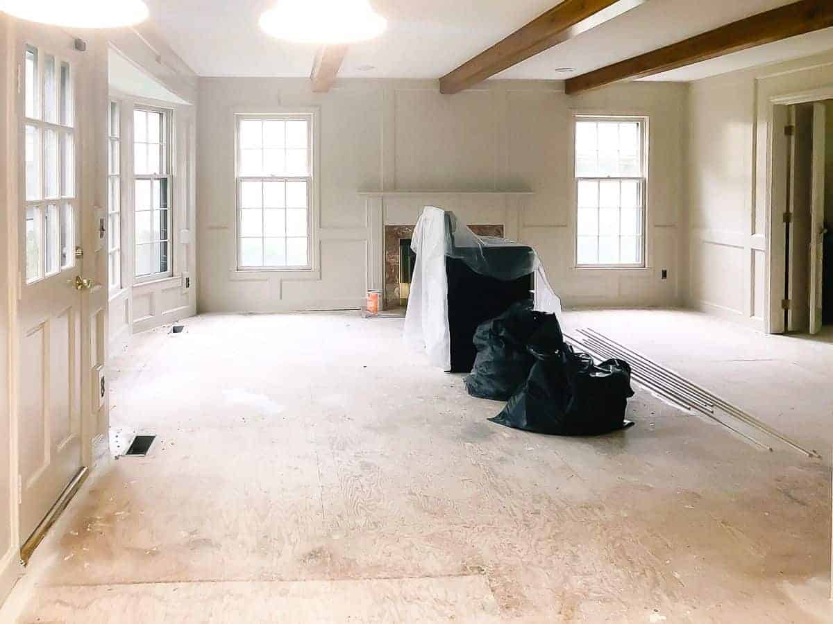 A large living room mid-renovation, walls painted in Sherwin Williams Accessible Beige.