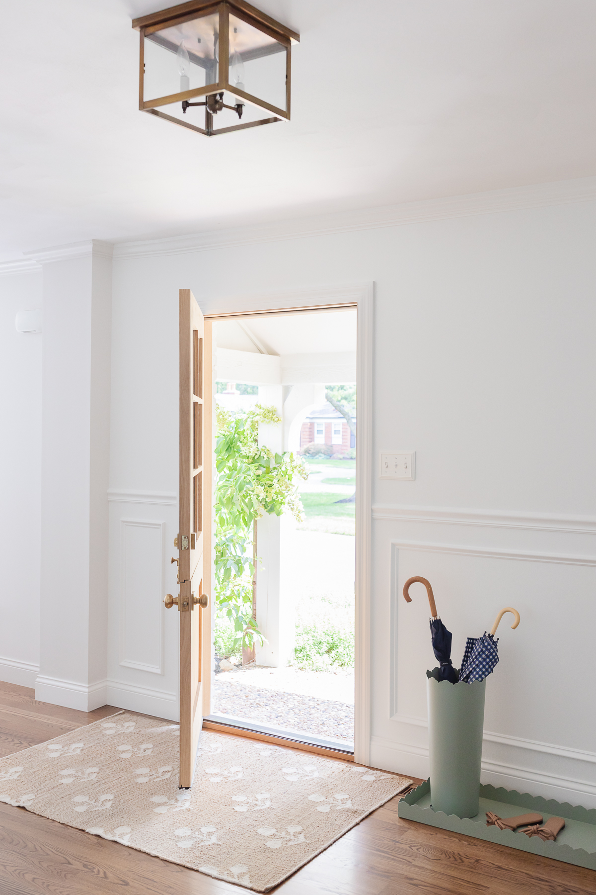 A white foyer design with a Dutch door, box trim moulding on the walls and hardwood floors.