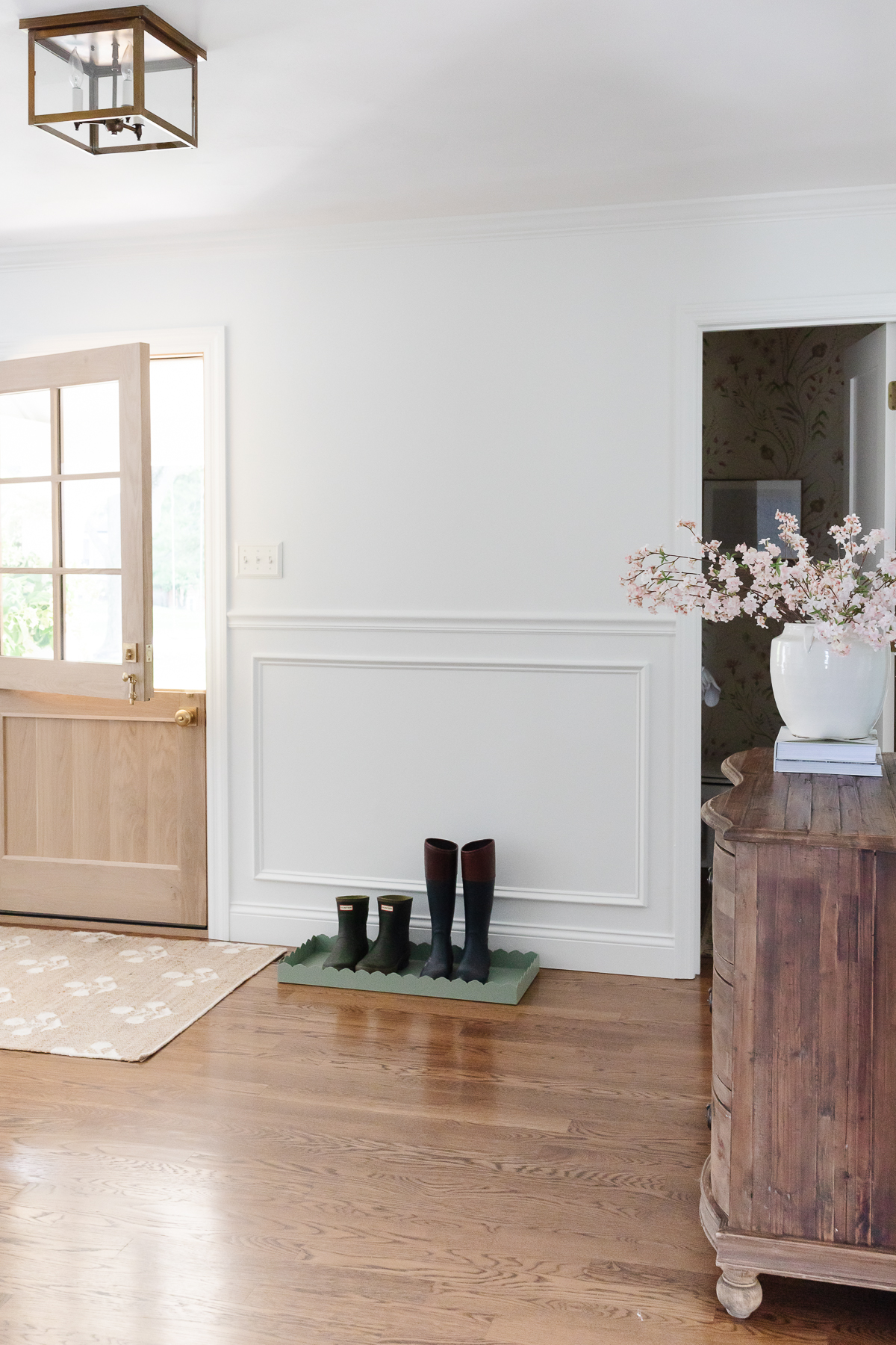 A white foyer design with a Dutch door, box trim moulding on the walls and hardwood floors.