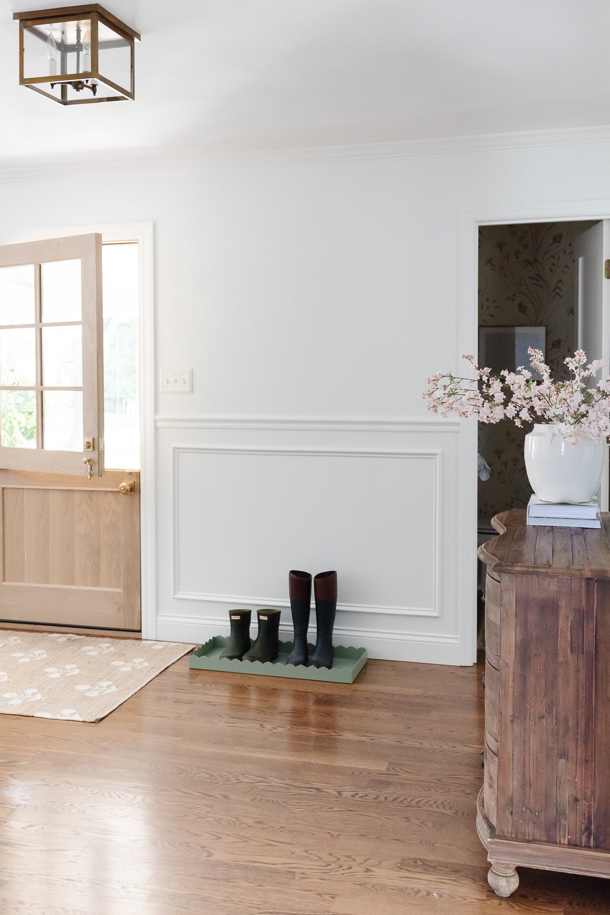 A white foyer design with a Dutch door, box trim moulding on the walls and hardwood floors.