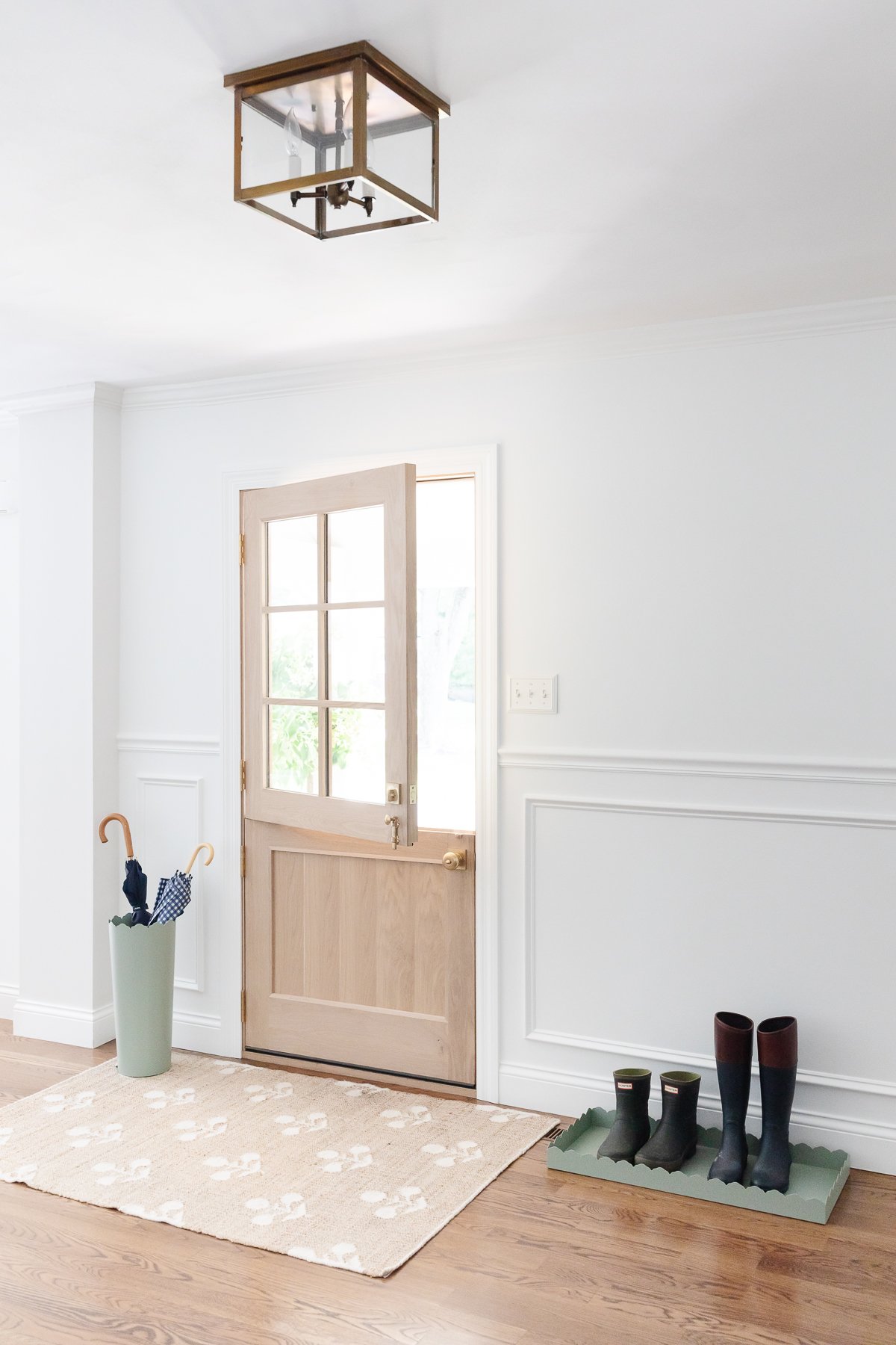 A white foyer design with a Dutch door, box trim moulding on the walls and hardwood floors.