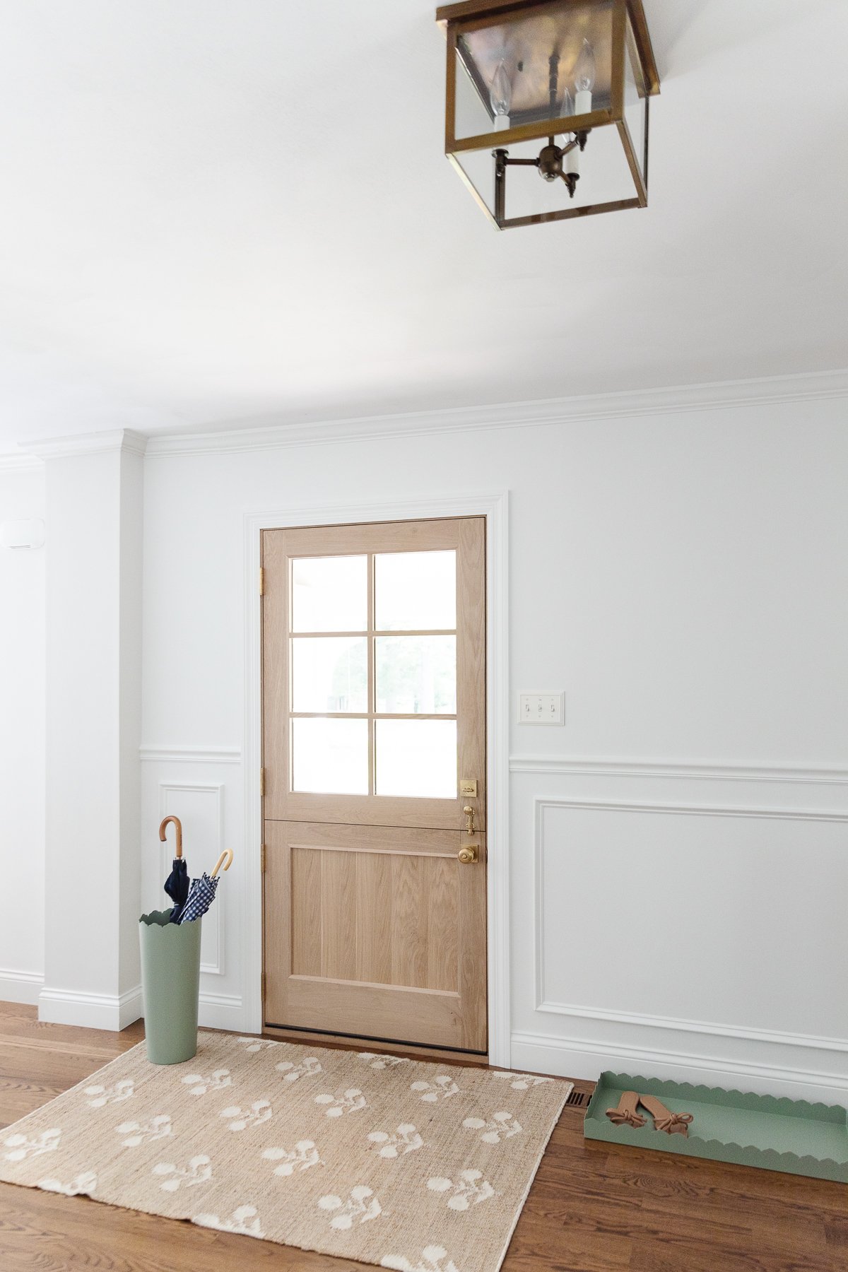 A white foyer design with a Dutch door, box trim moulding on the walls and hardwood floors. 