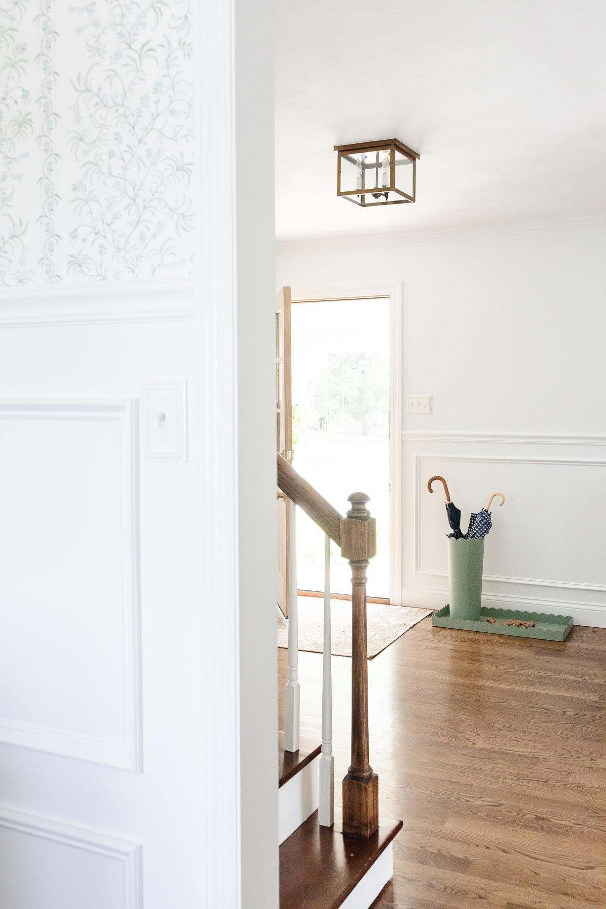 A white foyer design with box trim moulding on the walls and hardwood floors.