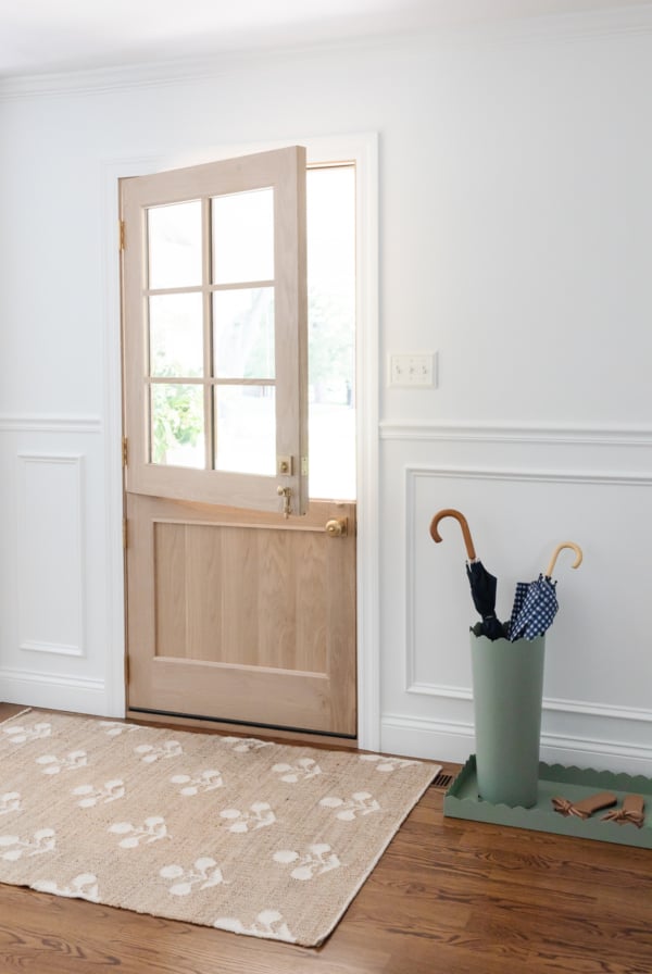 A white foyer design with a Dutch door, box trim moulding on the walls and hardwood floors.