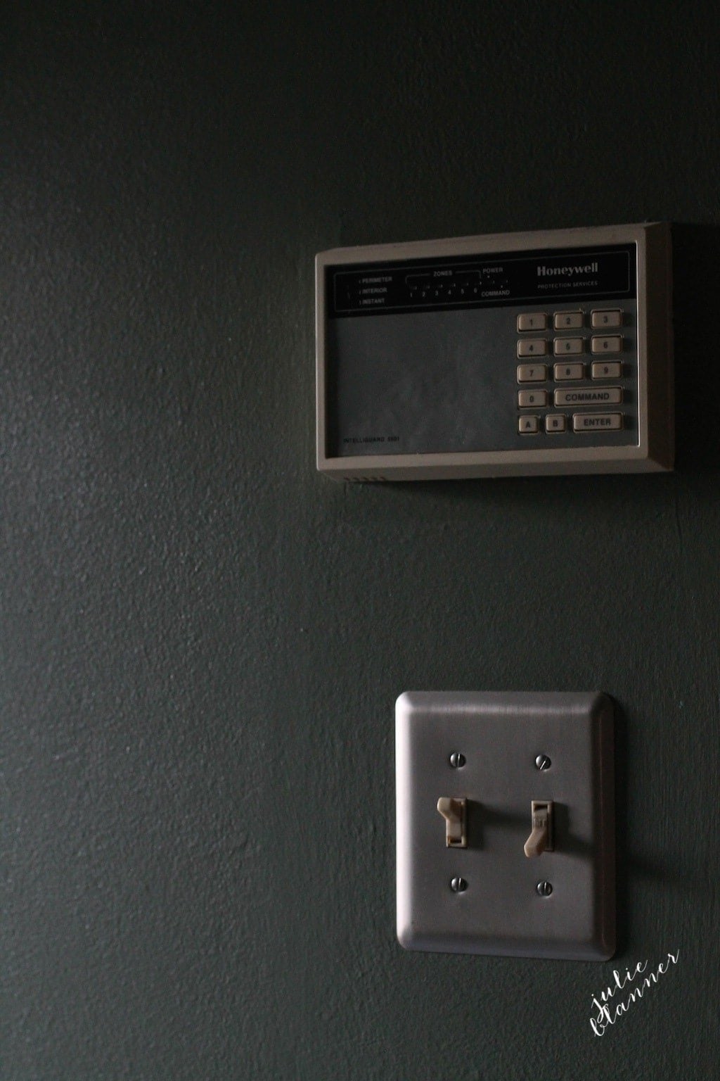 A black wall with a dated intercom system in an old home.