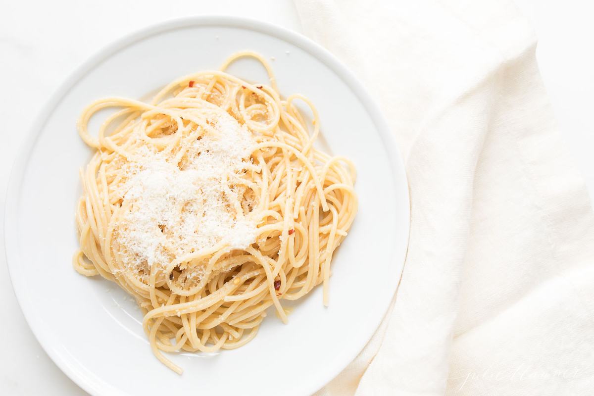 pasta aglio e olio on a white plate with napkin to the side