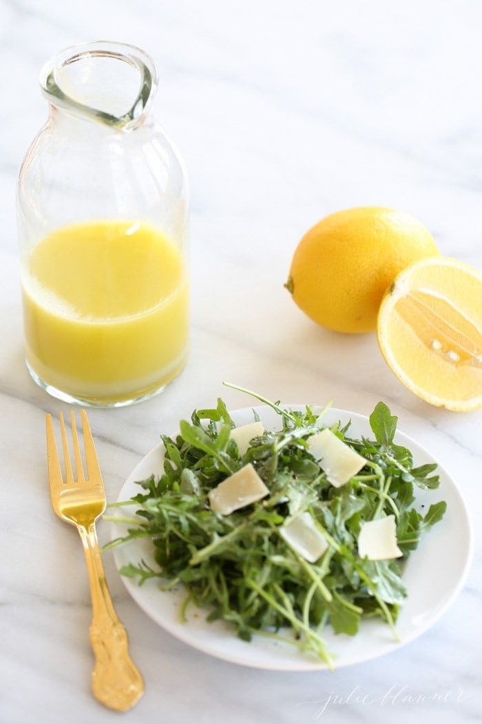 Arugula salad next to a bottle of lemon dressing