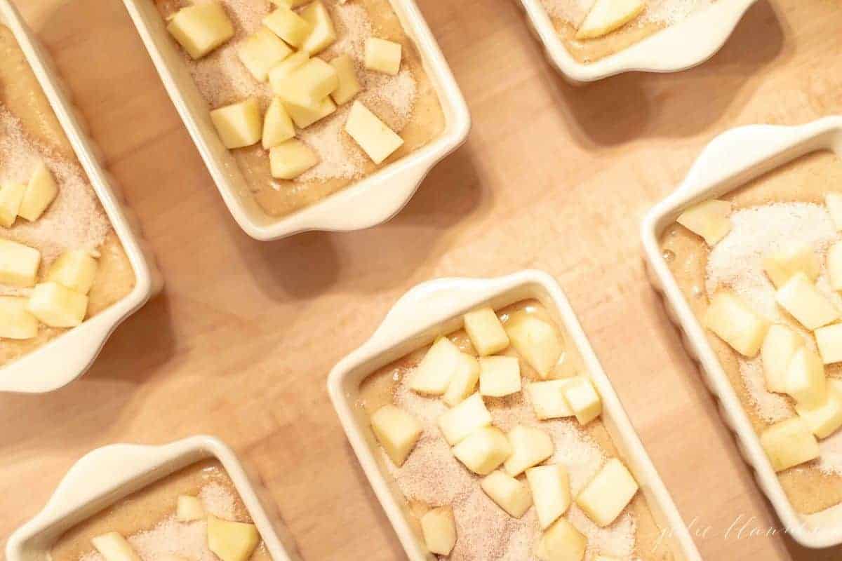 Small white ceramic loaf pans filled with apple cinnamon quick bread batter. #applequickbread