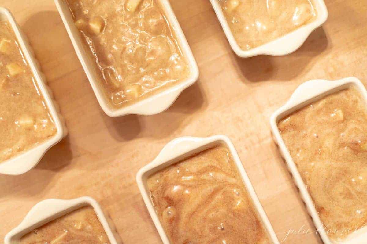 Small white ceramic loaf pans filled with apple cinnamon quick bread batter. #applequickbread
