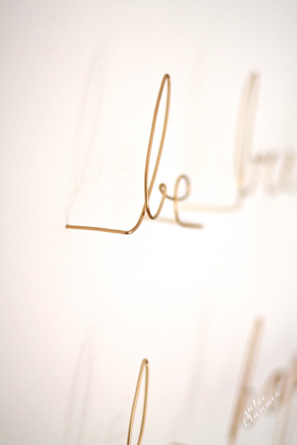 Gold wire wall art shaped into the words "be bright be happy be you"