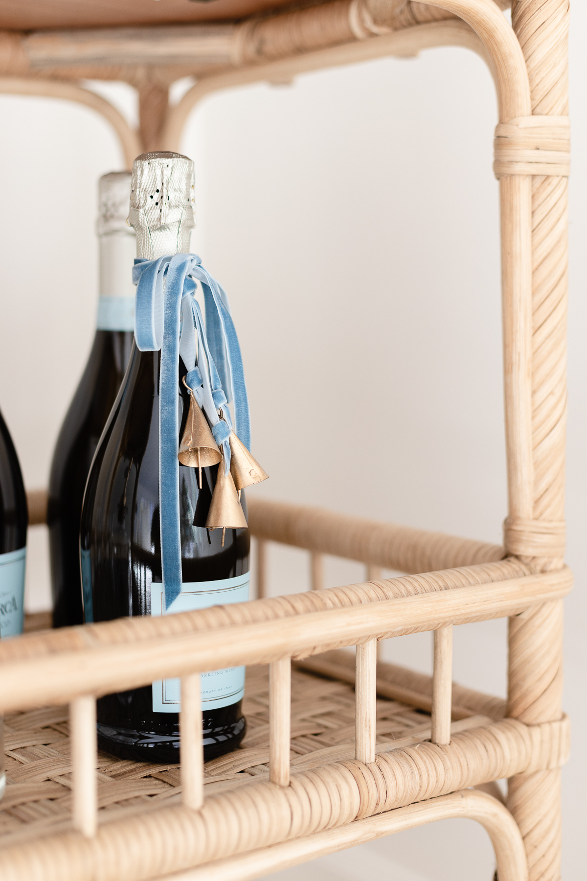 A bottle of champagne on a rattan bar cart styled for Christmas