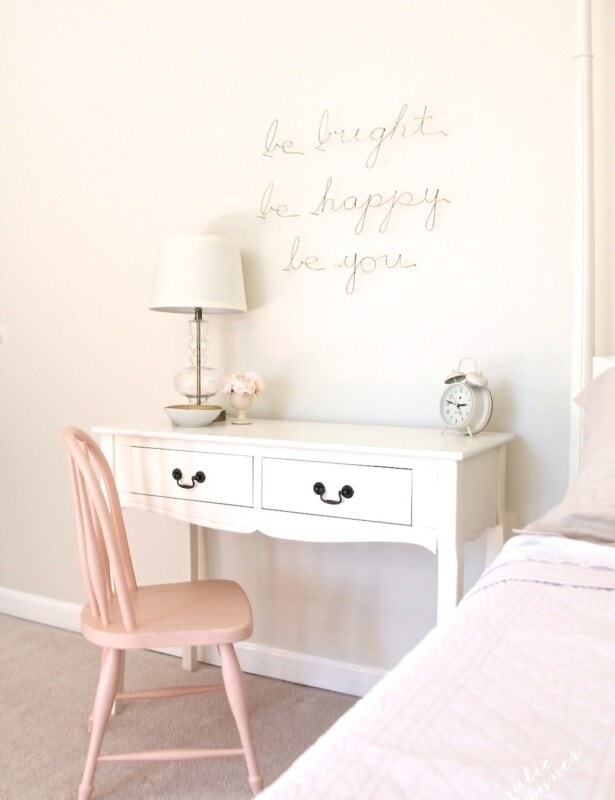 A white side table desk with a pink chair in a little girl's bedroom.