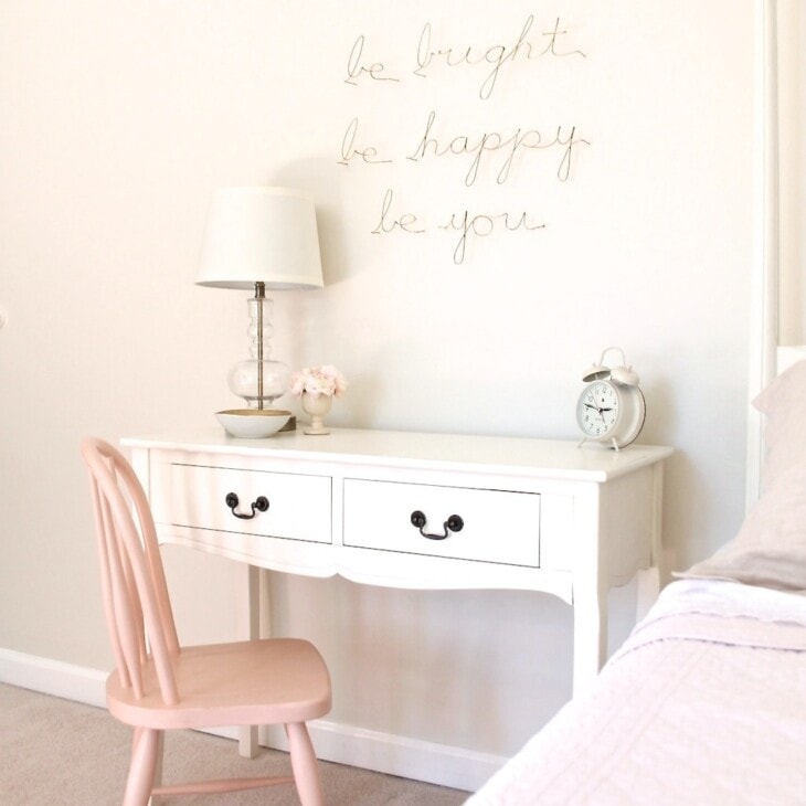 A white side table desk with a pink chair in a little girl's bedroom.