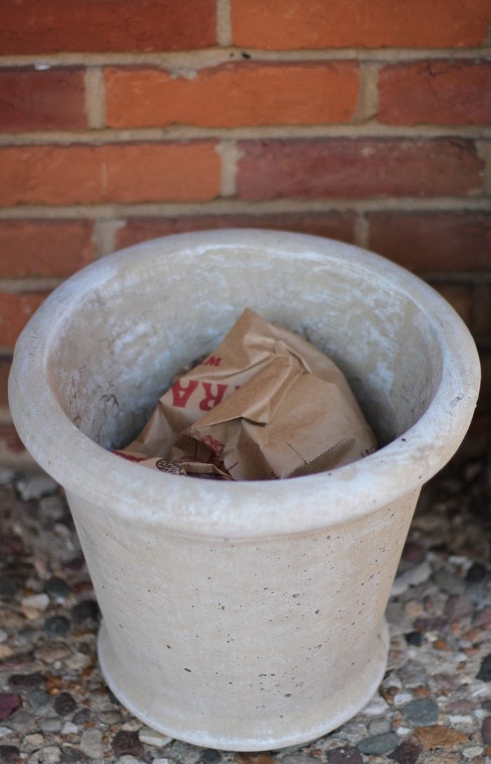 Planter with crumpled paper bag at the bottom forms the base of the outdoor winter arrangement