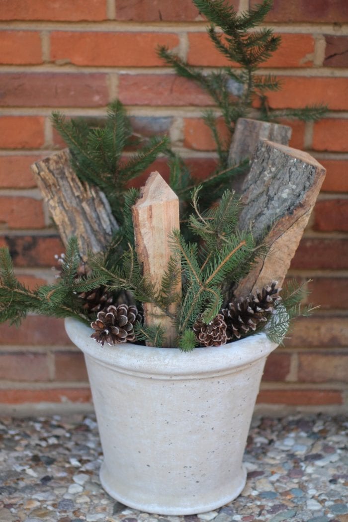 Branches of evergreens and pinecones are added to the winter arrangement