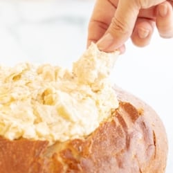 A bread bowl filled with artichoke dip