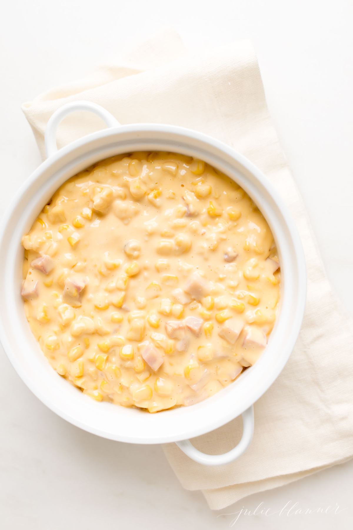 A white casserole dish filled with Cheesy Corn Casserole. 