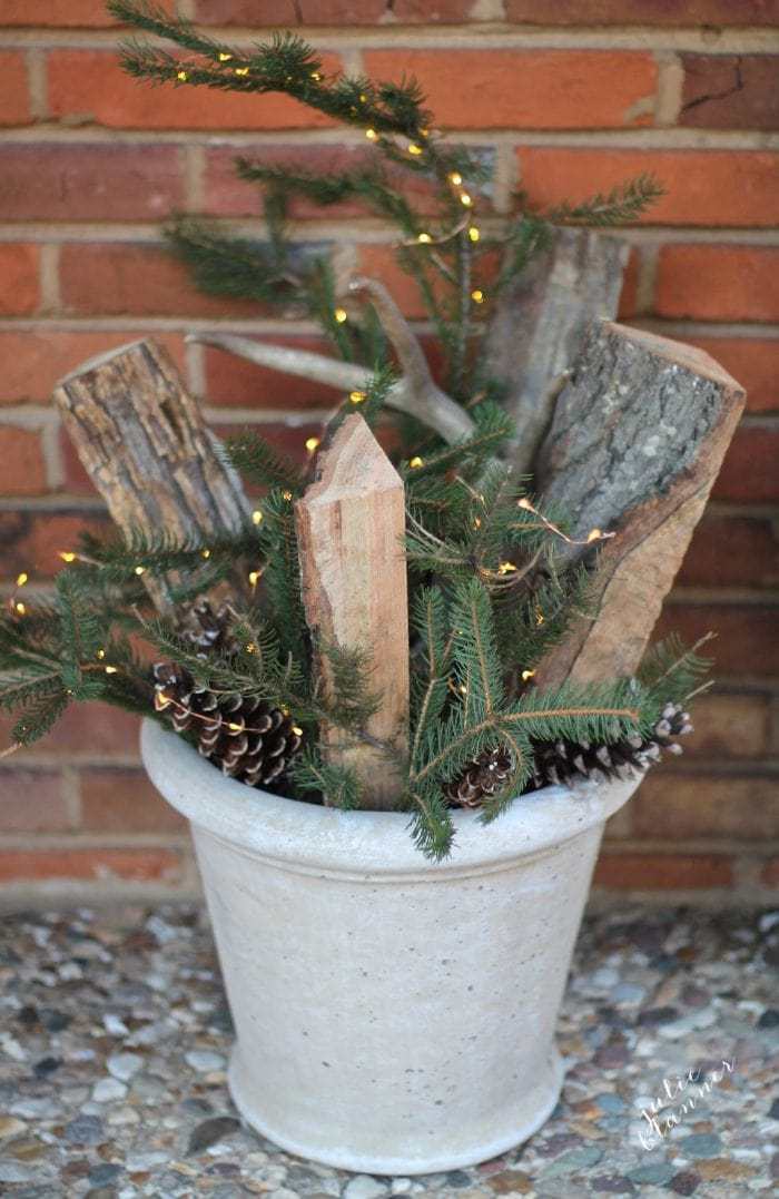 Simple planter filled with evergreens, wooden logs and pinecones