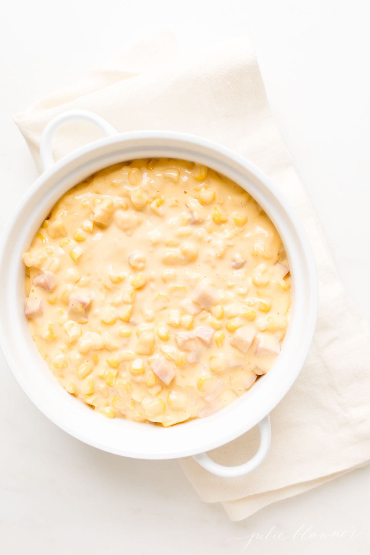 A white casserole dish filled with creamy corn casserole.