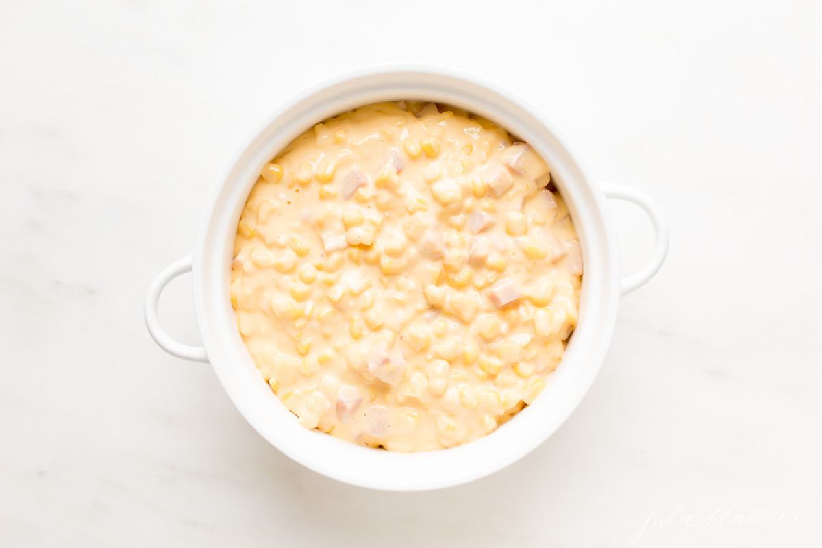A white casserole dish filled with Cheesy Corn Casserole. 