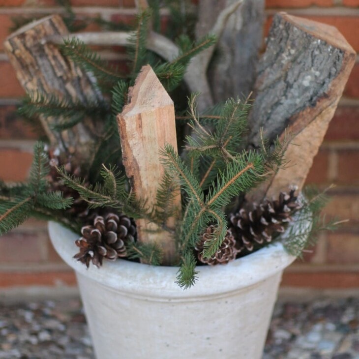 fall flower arrangement in pot with antlers wood pinecone and branches