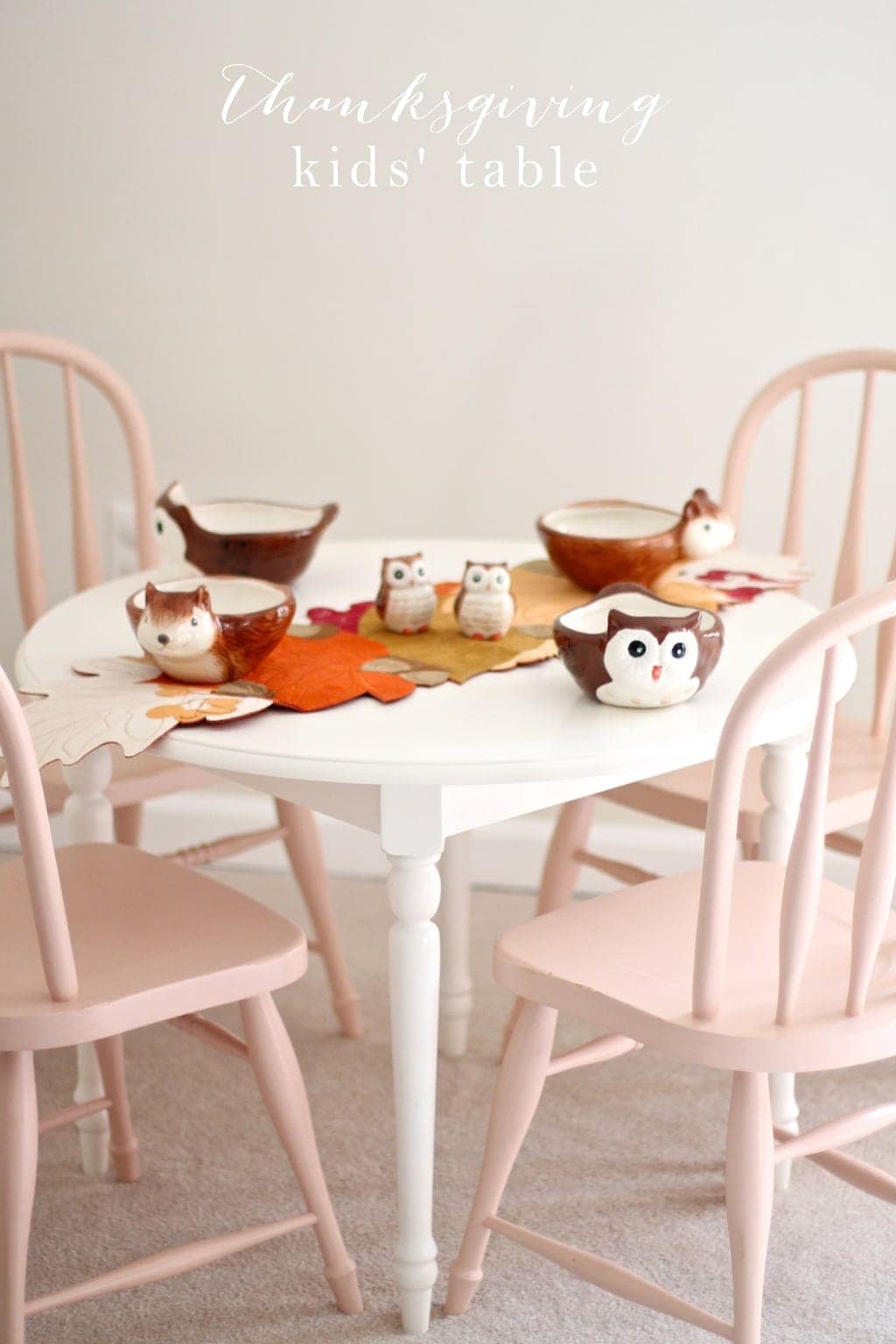 Thanksgiving kids' table set with fall decor and pink chairs.