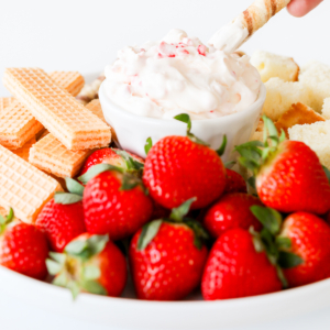 A plate with strawberries and sweet dip on it.
