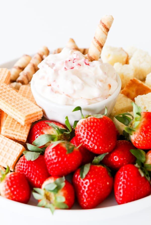A plate with strawberries, crackers, and sweet dip.