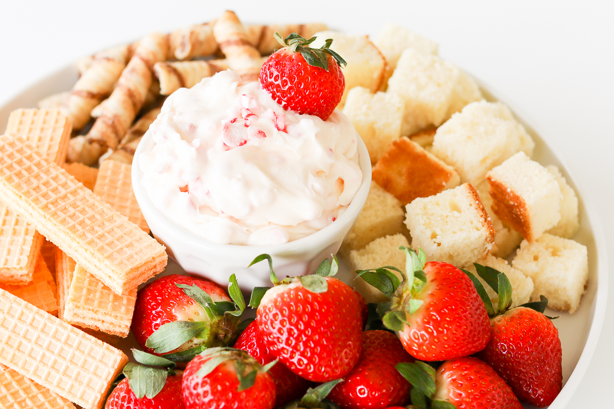 A plate with strawberries and a sweet fruit dip.