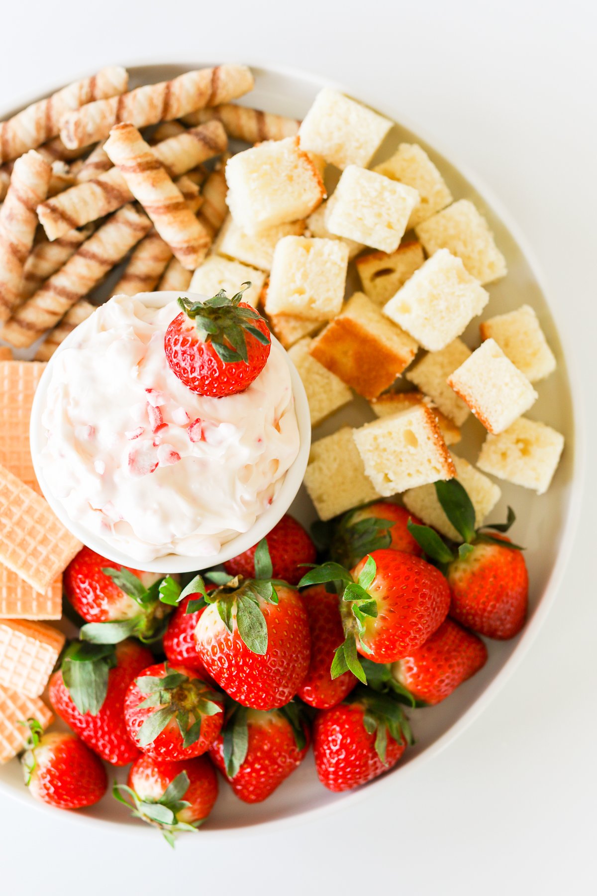 A plate with strawberries, crackers, and a sweet fruit dip.