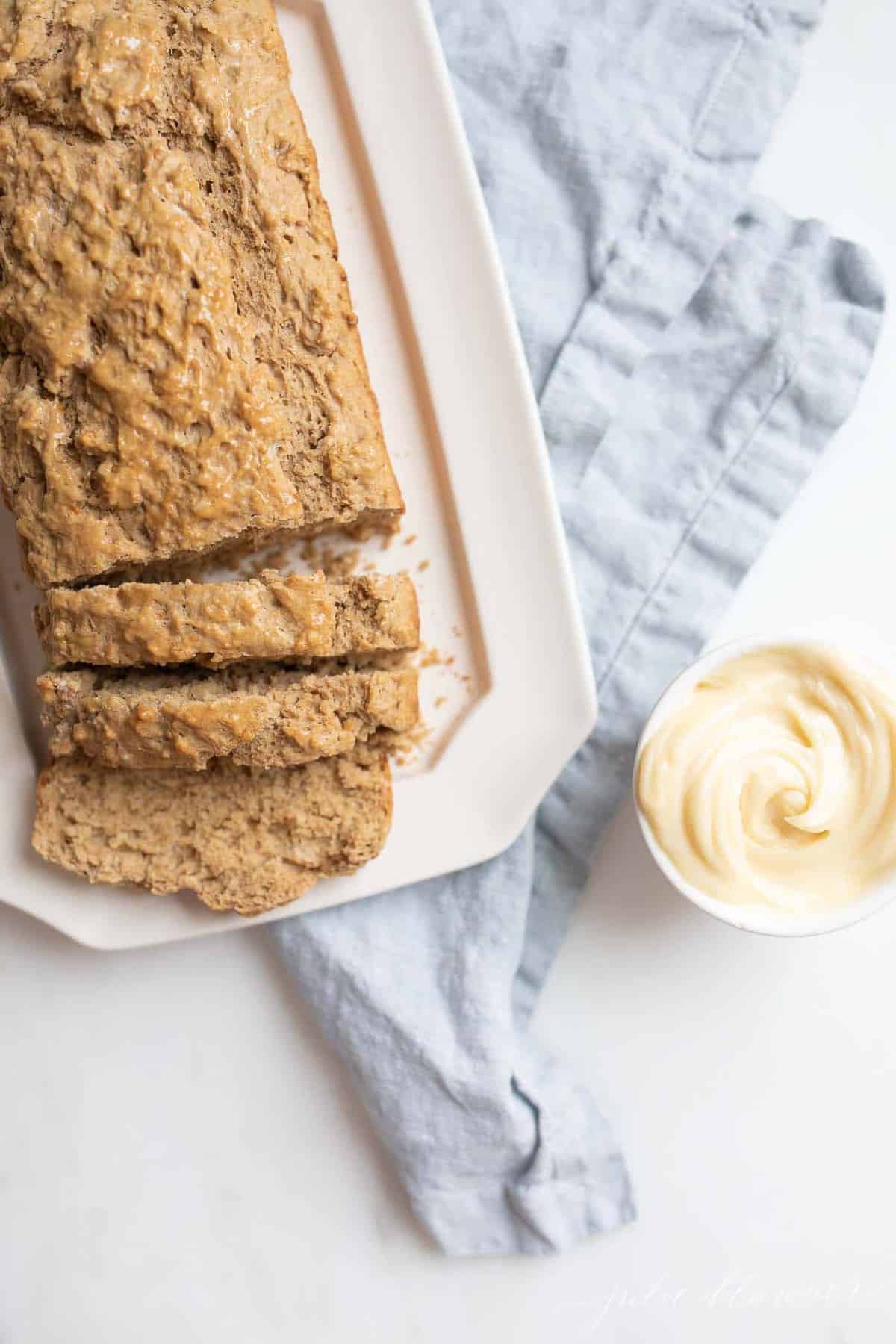 A platter of sliced bread with a bowl of honey butter next to it for an array of thanksgiving recipes
