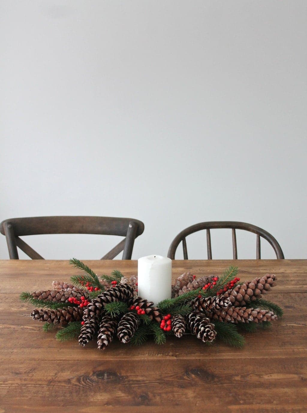 A christmas pinecone centerpiece on a farm table.
